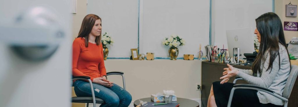 a woman sitting down speaking with a counselor 