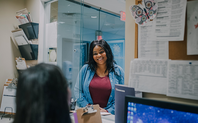 woman smiling at another woman working at the front desk