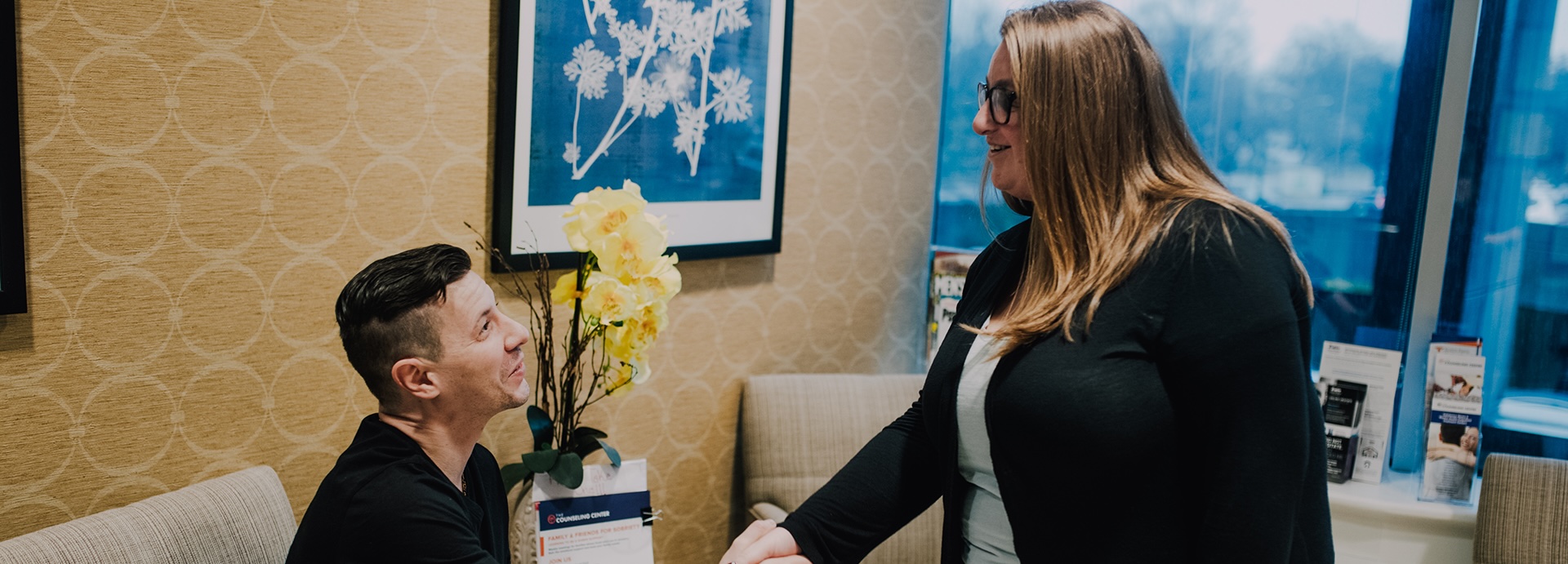 man sitting down shacking a woman's hand