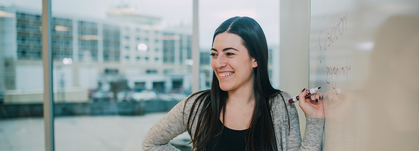 woman writing on a whiteboard smiling
